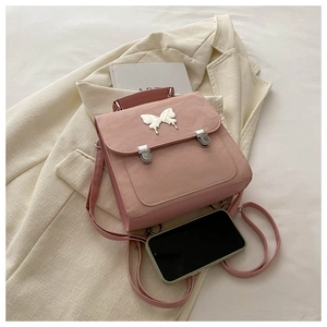 Detailed macro shot of a pink leather backpack with a silver butterfly logo and vintage buckles