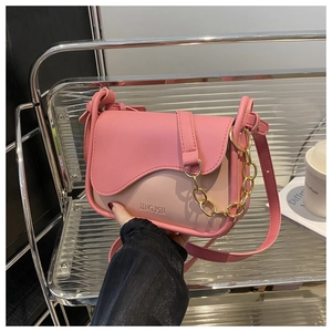 Dettaglio della borsa a tracolla bicolore rosa con patta a onda e catena dorata decorativa
