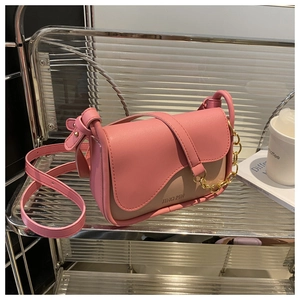 Dettaglio borsa a sella rosa e beige con tracolla a catena e patta di chiusura