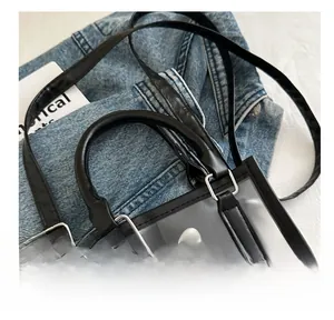 Détail du sac cabas transparent en PVC avec bordures en similicuir noir et boucles argentées