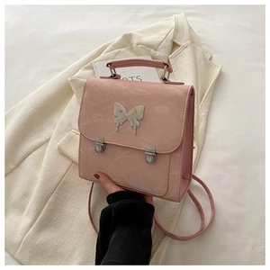 Detailed view of pink PU leather backpack with butterfly buckle on a beige blazer