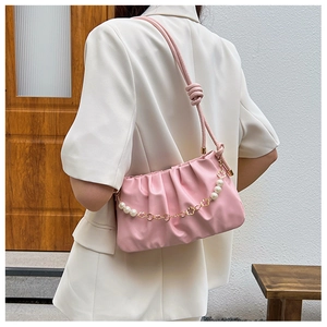 Detail of pink pleated cloud bag featuring pearl and gold metal floral chain accent