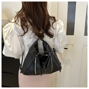 Détail du sac à épaule en cuir noir avec zips argentés et nœuds décoratifs sur le dos