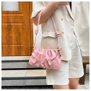 Pink pleated crossbody bag with pearl and floral chain shown on models shoulder