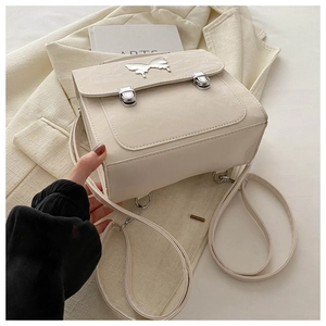 Detail of cream glossy backpack featuring silver butterfly buckle and double square locks