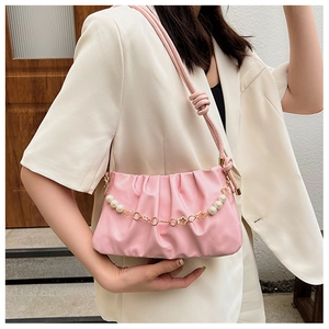 Detail of pink pleated underarm bag featuring a pearl and gold floral decorative chain