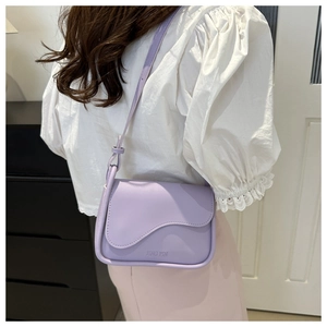 Dettaglio borsa lilla in pelle PU con patta ondulata e decorazione a nodo sulla tracolla