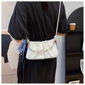 Detail of white pleated cloud bag featuring elegant pearl and gold chain decoration