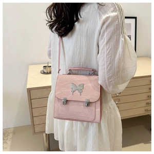 Detail of pink faux leather bag featuring a large silver butterfly metal buckle and clasp