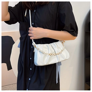 Detail of white pleated shoulder bag with gold chain and pearl flower pendant