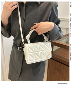 Detail of white quilted crossbody bag with gold metal hardware and knotted handle