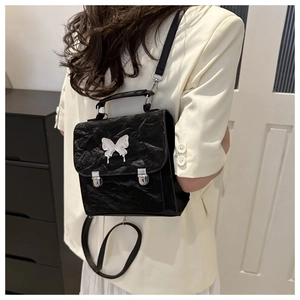 Detail of a black chic backpack with silver liquid metal butterfly and dual buckles