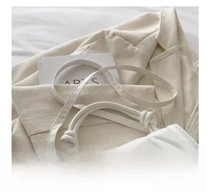 Detail of white quilted crossbody bag with woven knot handle and adjustable strap