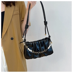 Detail of black pleated shoulder bag with pearl and gold floral chain accessory