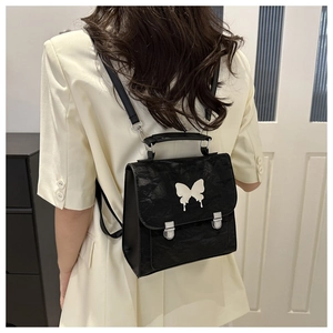 Detail of a black leather backpack with a unique liquid-style silver butterfly buckle