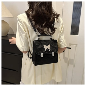 Detail of a chic black backpack with silver butterfly hardware and pleated leather texture