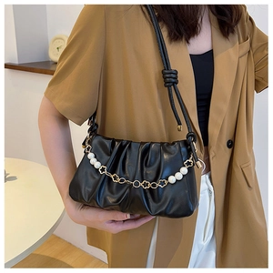 Close-up of black pleated cloud bag with elegant pearl and gold flower chain strap
