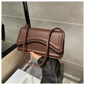 Detailed view of dark brown shoulder bag with unique wave stitching and dual straps