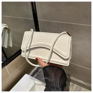 Close-up of cream white shoulder bag with unique curved layered stitching and gold metal hardware