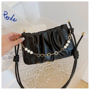 Detail of ruched black cloud bag featuring decorative pearl and gold flower chain