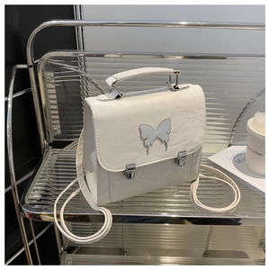 Detailed view of a white leather backpack featuring a silver fluid butterfly metal buckle