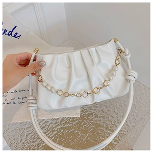 Detail of white pleated shoulder bag featuring elegant pearl and floral gold chain strap