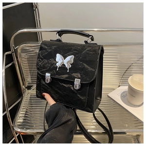 Close-up of black wrinkled leather backpack featuring a silver butterfly buckle and twin locks