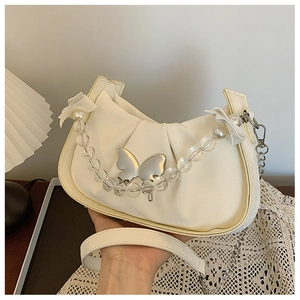 Detail of cream pleated crescent bag with metal butterfly buckle and pearl beaded handle