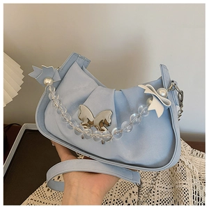 Close-up of light blue pleated handbag with silver butterfly buckle and beaded handle