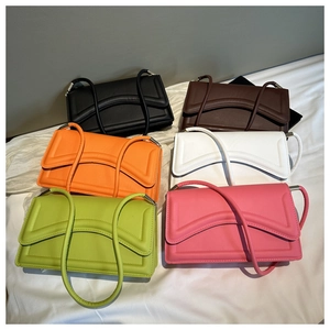Flat lay of small rectangular shoulder bags in six vibrant colors with wavy quilting
