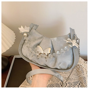 Close-up of metallic blue saddle bag featuring beaded pearl chain and silver butterfly buckle