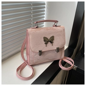 Detailed view of pink textured backpack featuring a silver butterfly metallic ornament