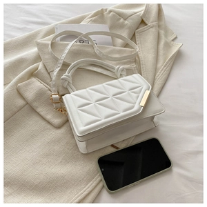 Close-up of white quilted mini handbag with textured handle and gold metal detail