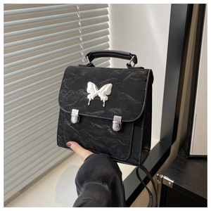 Detail of black pleated texture bag with silver butterfly buckle and metallic clasps