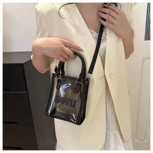 Détail d'un petit sac cabas transparent avec bordure noire et lettrage OWU porté
