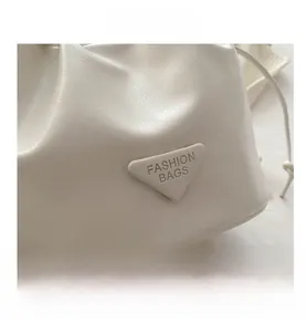 Detail view of white ruched leather bucket bag with embossed triangular logo plaque