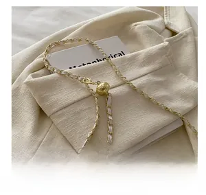 Detail of adjustable gold chain strap with woven white leather and metal ball slider