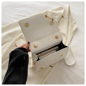 Detailed interior of a white square crossbody bag showing magnetic buckles and storage space