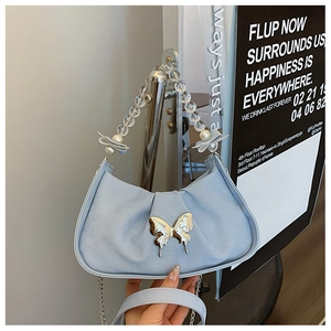 Detail of light blue crossbody bag featuring beaded pearl handle and silver metal chain