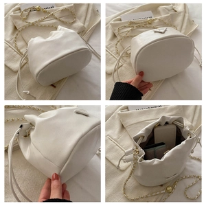 Detail of white drawstring bucket bag showing gold chain strap and interior storage capacity