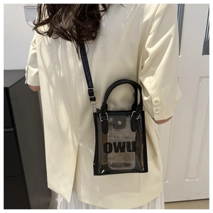 Détail d'un mini sac bandoulière en PVC transparent avec bordure noire et logo OWU