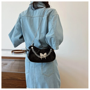 Detailed close-up of a black velvet crescent bag with silver butterfly and beaded chains