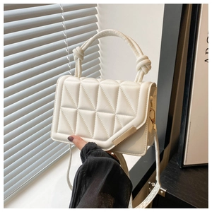 Detail of cream white quilted crossbody bag featuring knotted handle and metal buckle