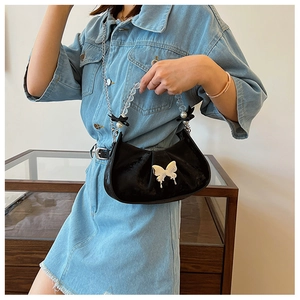 Detail of black pleated shoulder bag featuring a silver butterfly buckle and beaded handle