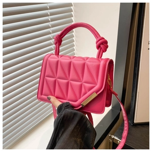 Close-up of rose pink quilted handbag with 3D triangular stitching and gold metal bar