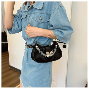 Detailed view of black velvet underarm bag with silver butterfly and beaded chain charm