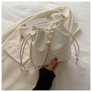 Detail of white leather drawstring bucket bag with gold chain and metal sphere adjuster