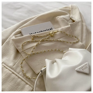 Detail of cream drawstring bucket bag with gold chain and fashion triangle logo