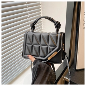 Detail shot of black quilted handbag with geometric triangle pattern and knot handle