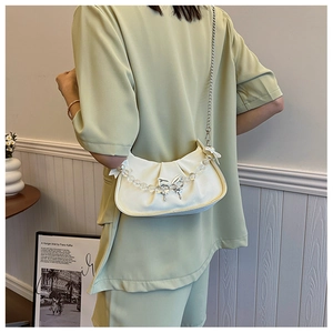 Detail of white pleated moon bag with silver butterfly buckle and beaded handle